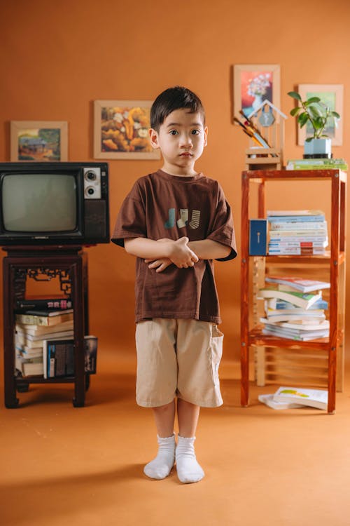 A boy standing in front of a television set