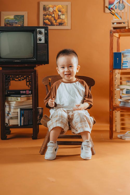 A young boy sitting in a chair in front of a television