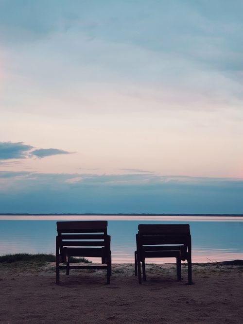 Free Two empty chairs facing a tranquil beach at sunset. Perfect for relaxation themes. Stock Photo