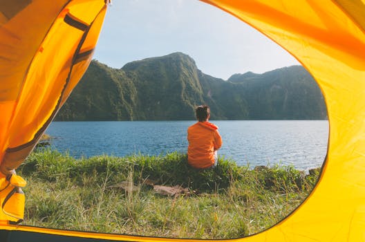 Serene view of a woman in a yellow tent, overlooking a picturesque lake and mountains in T'boli, Philippines.