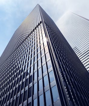 低角度拍摄多伦多市中心一座玻璃立面的时尚摩天大楼，捕捉到了阳光的光芒