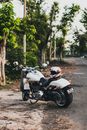 Photo of White Harley Davidson Fatboy Cruiser Motorcycle  with Helmet on Seat Parked by Side of Road Next to Trees
