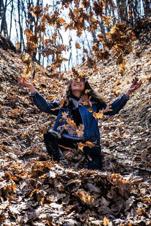 Фотография женщины в окружении засохших листьев