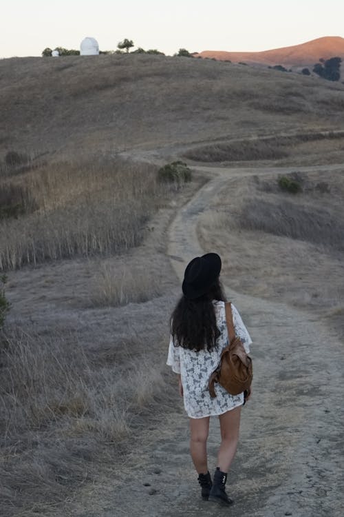 Tampilan Belakang Foto Wanita Berjalan Di Jalan Tanah Membawa Tas Coklat