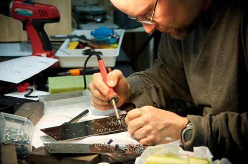 Precision board-level soldering on a damaged laptop mother board inside repair shop