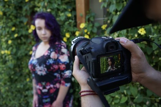 A photographer takes a portrait of a woman in a floral setting, showcasing photography in action.
