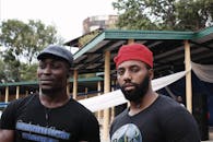 两名男子戴着耳机，穿着休闲帽和衬衫，站在户外