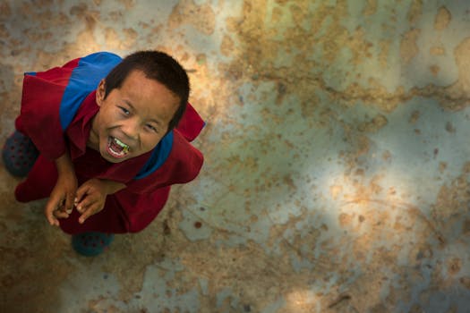 在柔和的灯光下，一个穿着色彩缤纷服装的小孩开心地笑着，被从上方拍摄下来