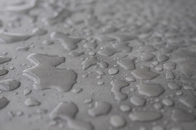 Gouttes d'eau perlant sur surface traitée hydrofuge
