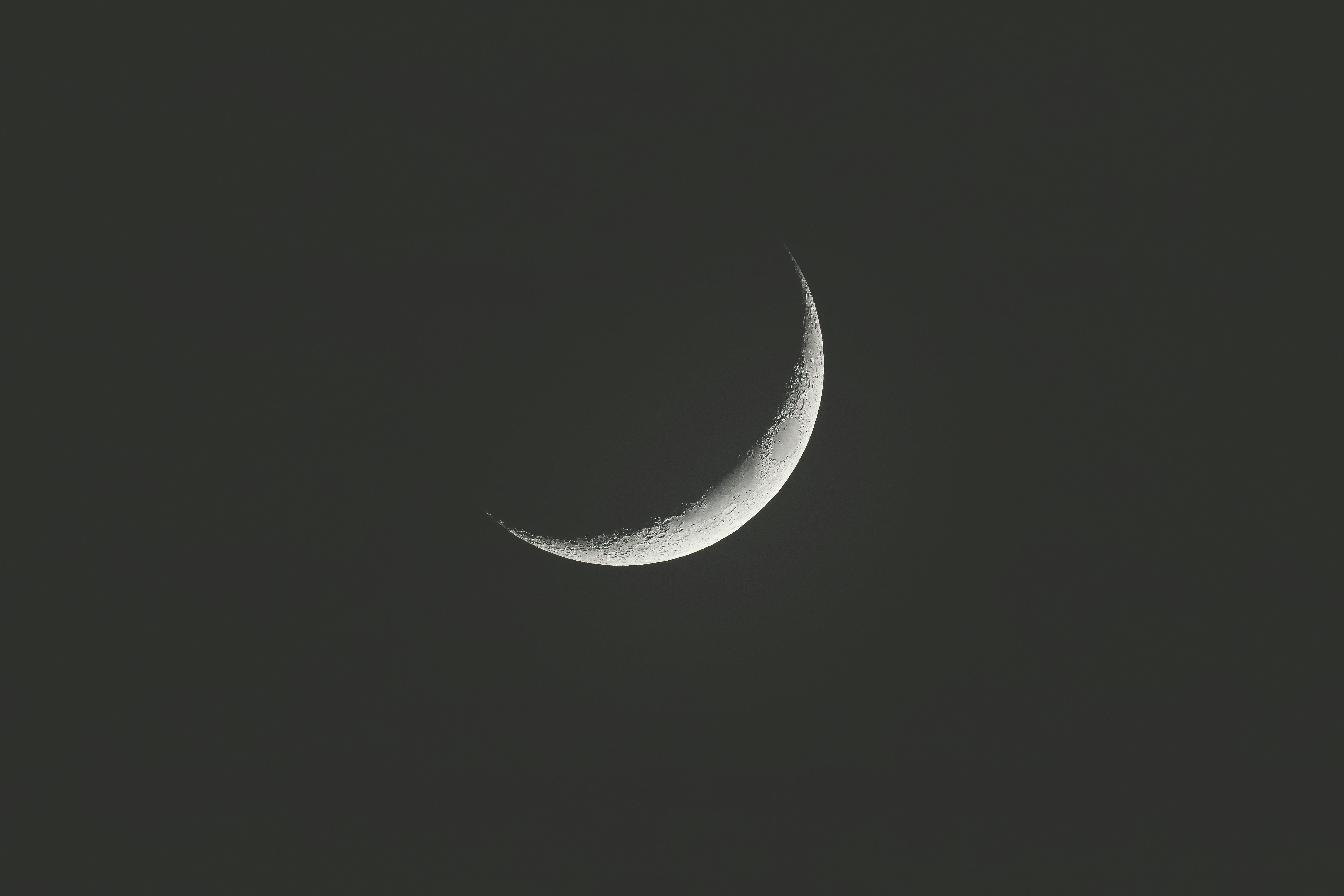 A serene crescent moon floating in the dark night sky, captured in India.