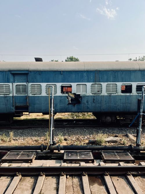 Free An abandoned blue train carriage on rustic railway tracks under a clear sky. Stock Photo