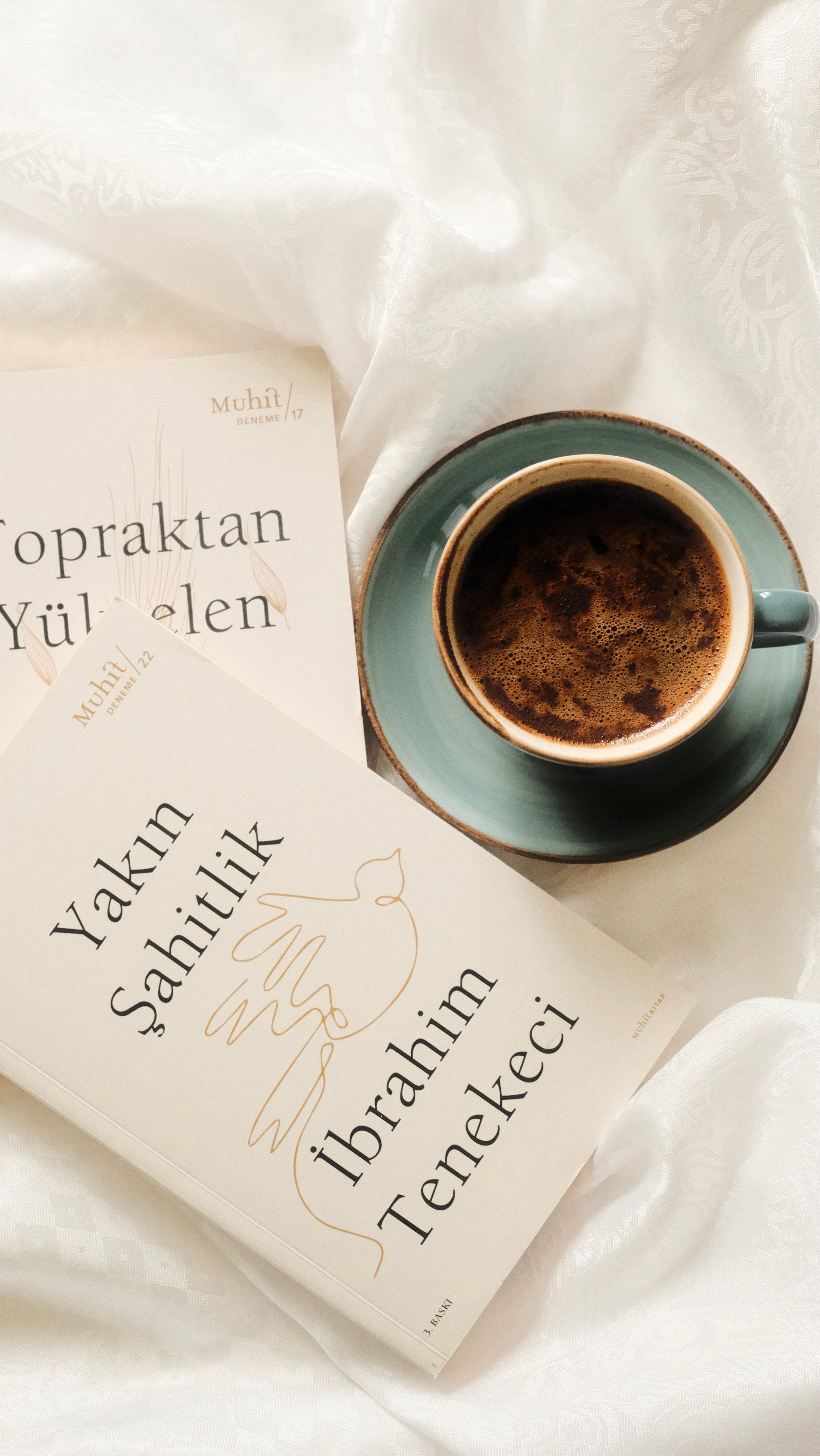 A comforting scene with coffee and Turkish literature on a bed, perfect for a relaxing morning.