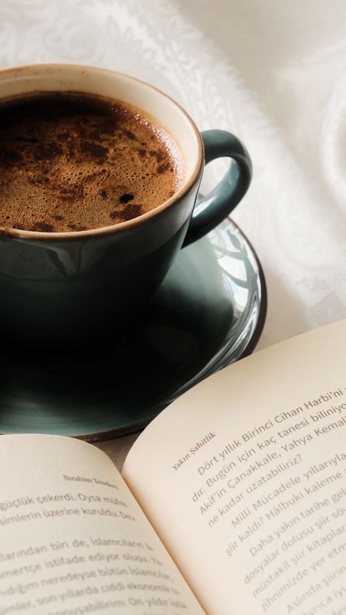 Free A cozy scene of a steaming coffee cup beside an open book, ideal for relaxation themes. Stock Photo