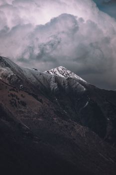 Majestic snow-capped mountain peaks surrounded by dramatic, moody clouds, offering a scenic view.