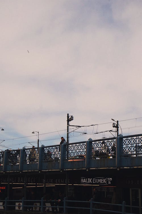 A person is walking on a bridge with a train in the background