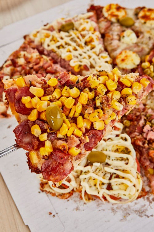 A pizza with corn, tomatoes and bacon on it