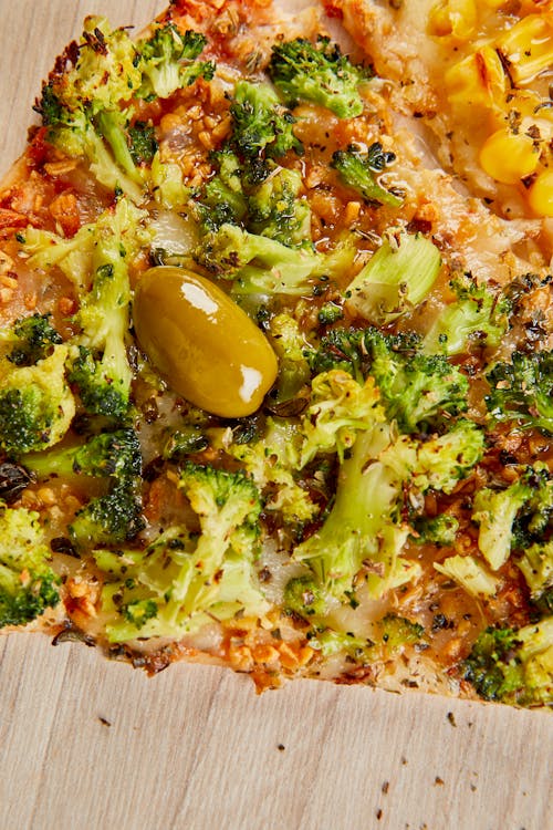 A pizza with broccoli and olives on it