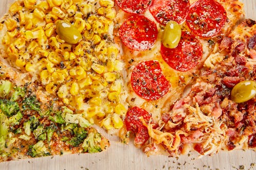 A pizza with corn, tomatoes, olives and cheese
