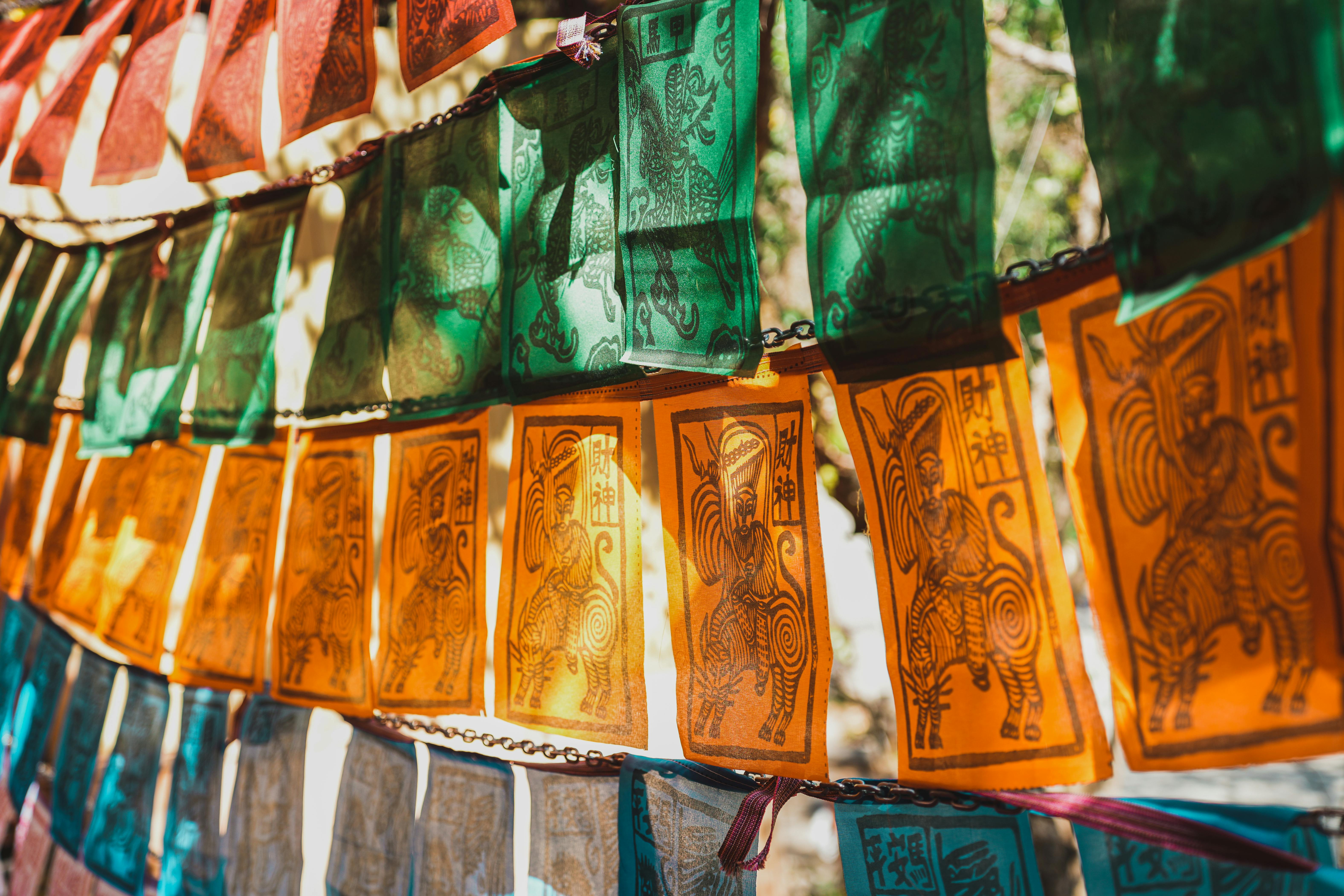 Vibrant prayer flags with intricate designs fluttering in outdoor sunlight.