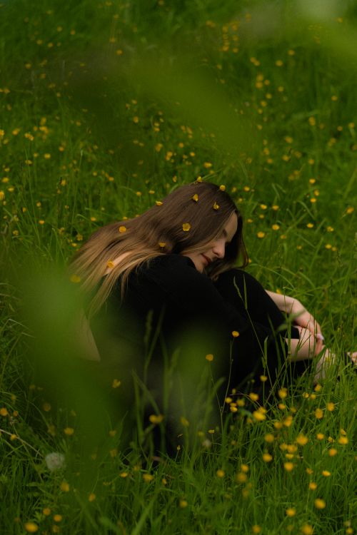 Free A serene moment of relaxation with a woman sitting among yellow wildflowers, embodying peace and natural beauty. Stock Photo