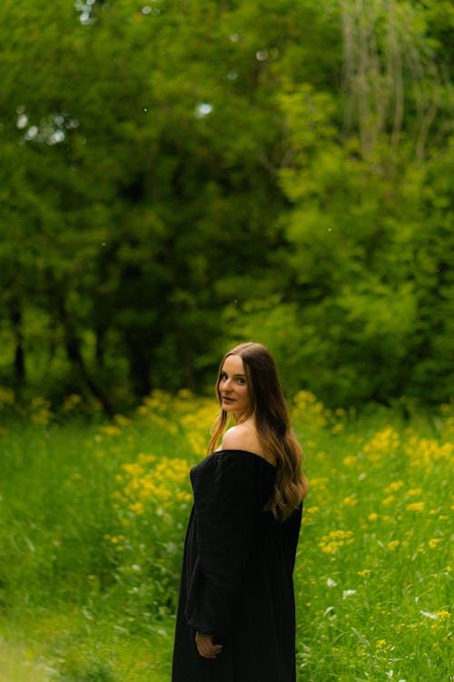 Woman in Loose Black Dress in a Meadow of Yellow Flowers