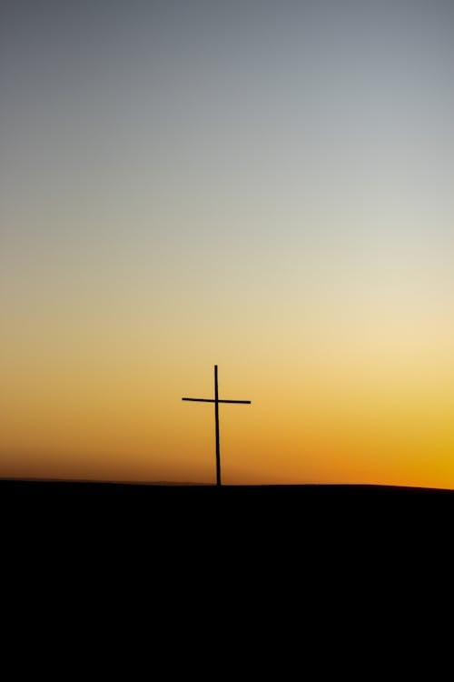 A cross is silhouetted against the sunset