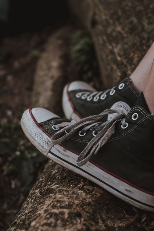 Free Casual black sneakers with shoelaces resting on a rock, highlighting texture and design. Stock Photo
