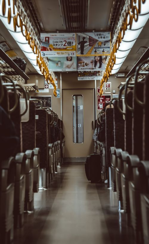 Free View of a Japanese train interior showing seats and hanging handles in a public transportation setting. Stock Photo