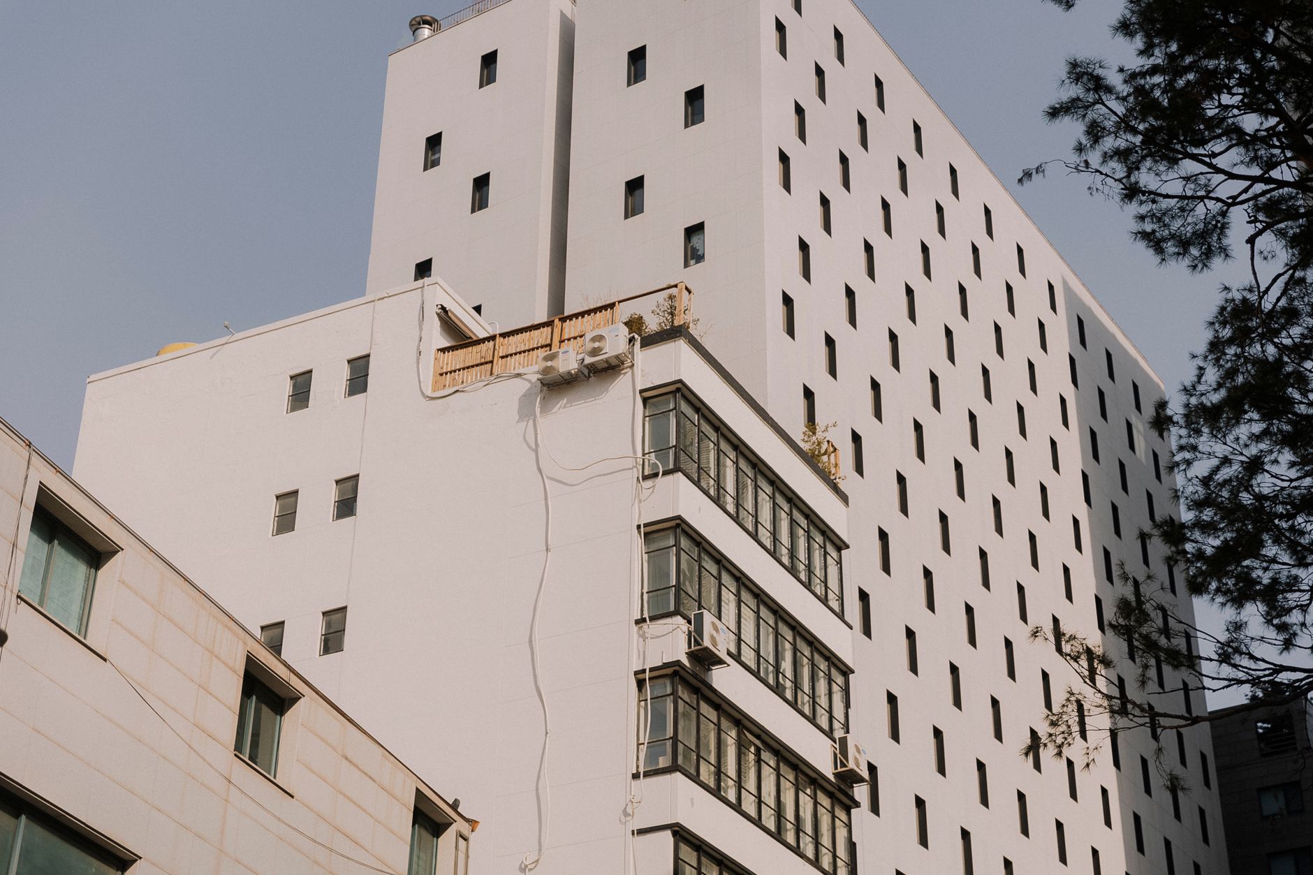 White urban building exterior with windows under the daylight, showcasing modern architecture.