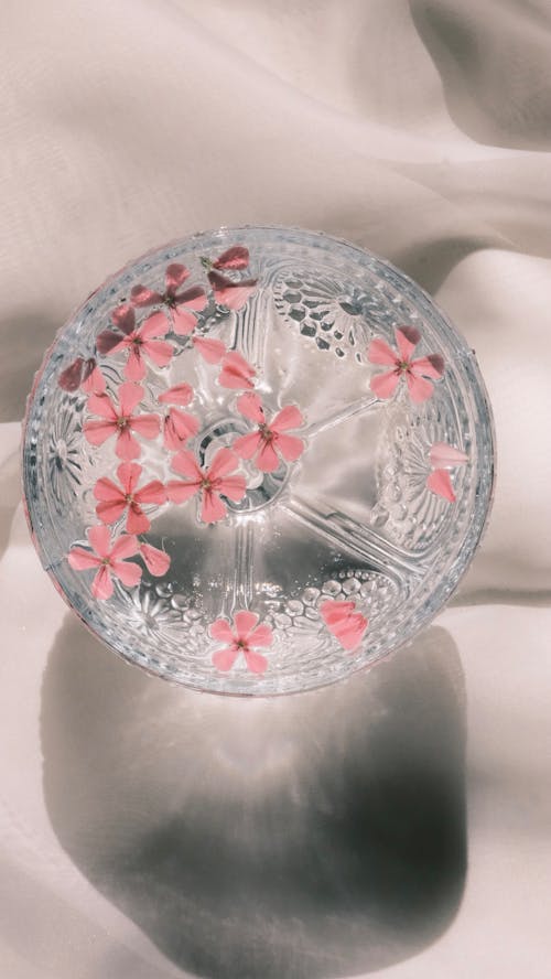 A glass with pink flowers on it sitting on a white surface