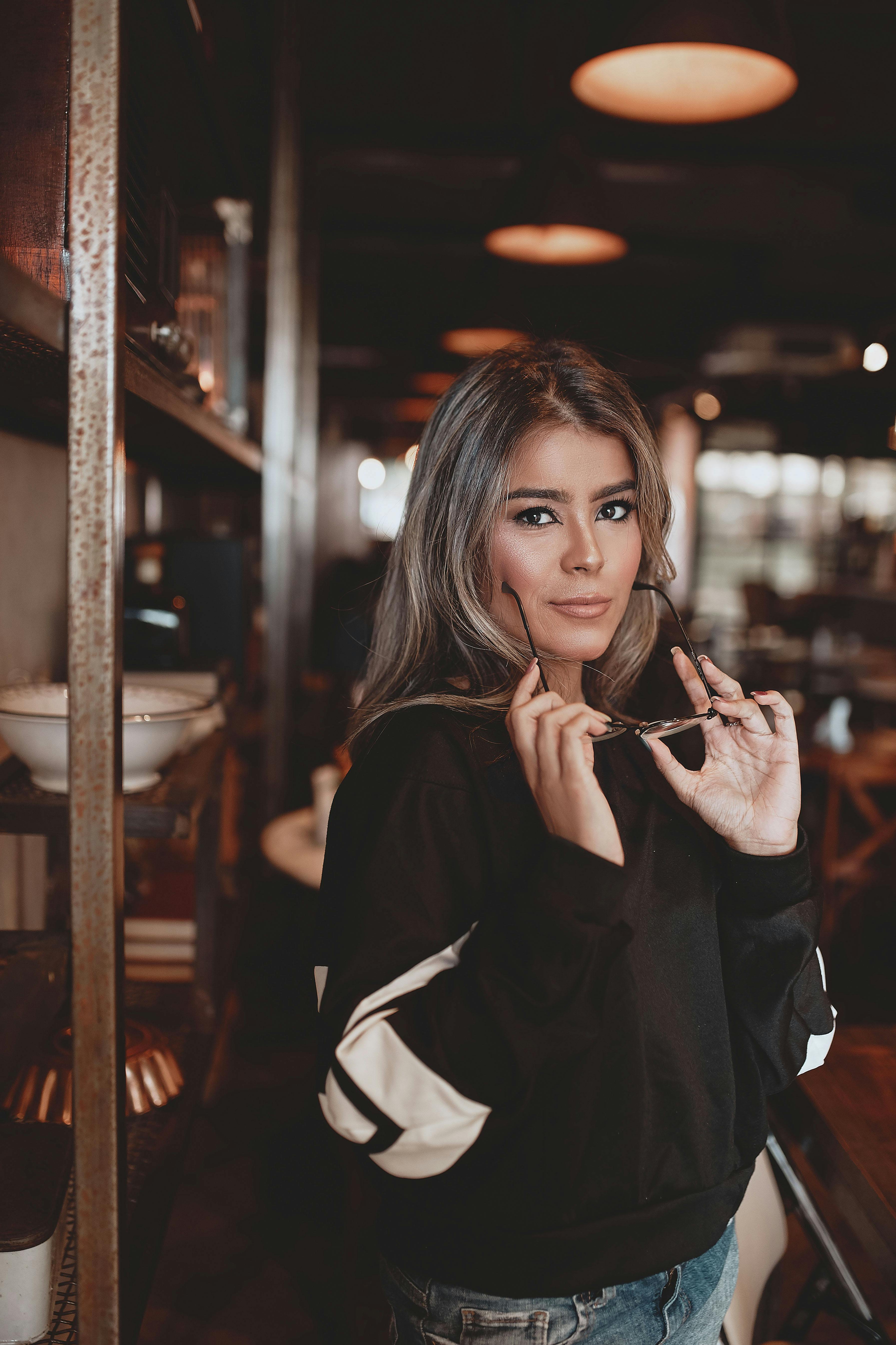 一名戴着眼镜的女子，在别致的咖啡馆里自信地摆着姿势