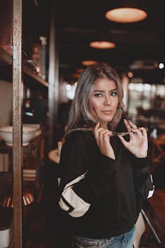 一名戴着眼镜的女子，在别致的咖啡馆里自信地摆着姿势