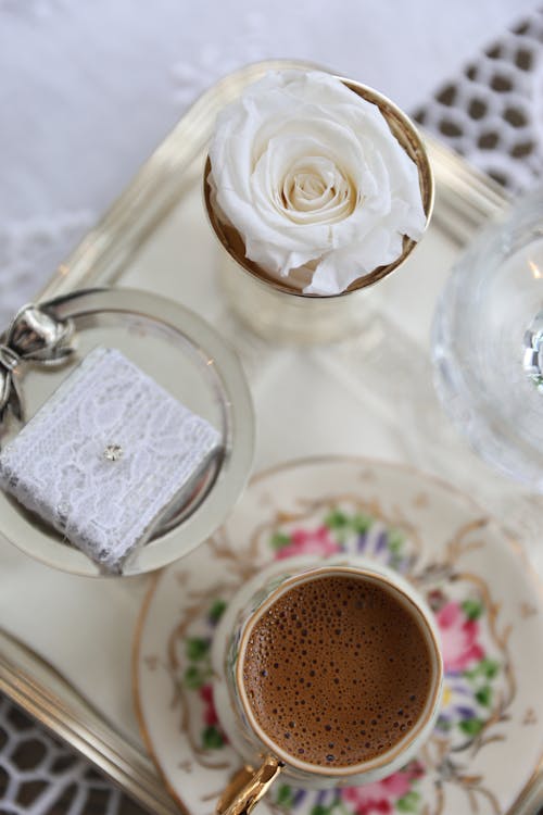 A tray with two cups and a white rose