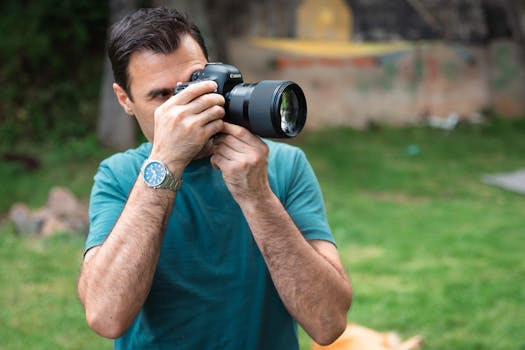Man with a camera taking pictures outdoors in a garden setting.