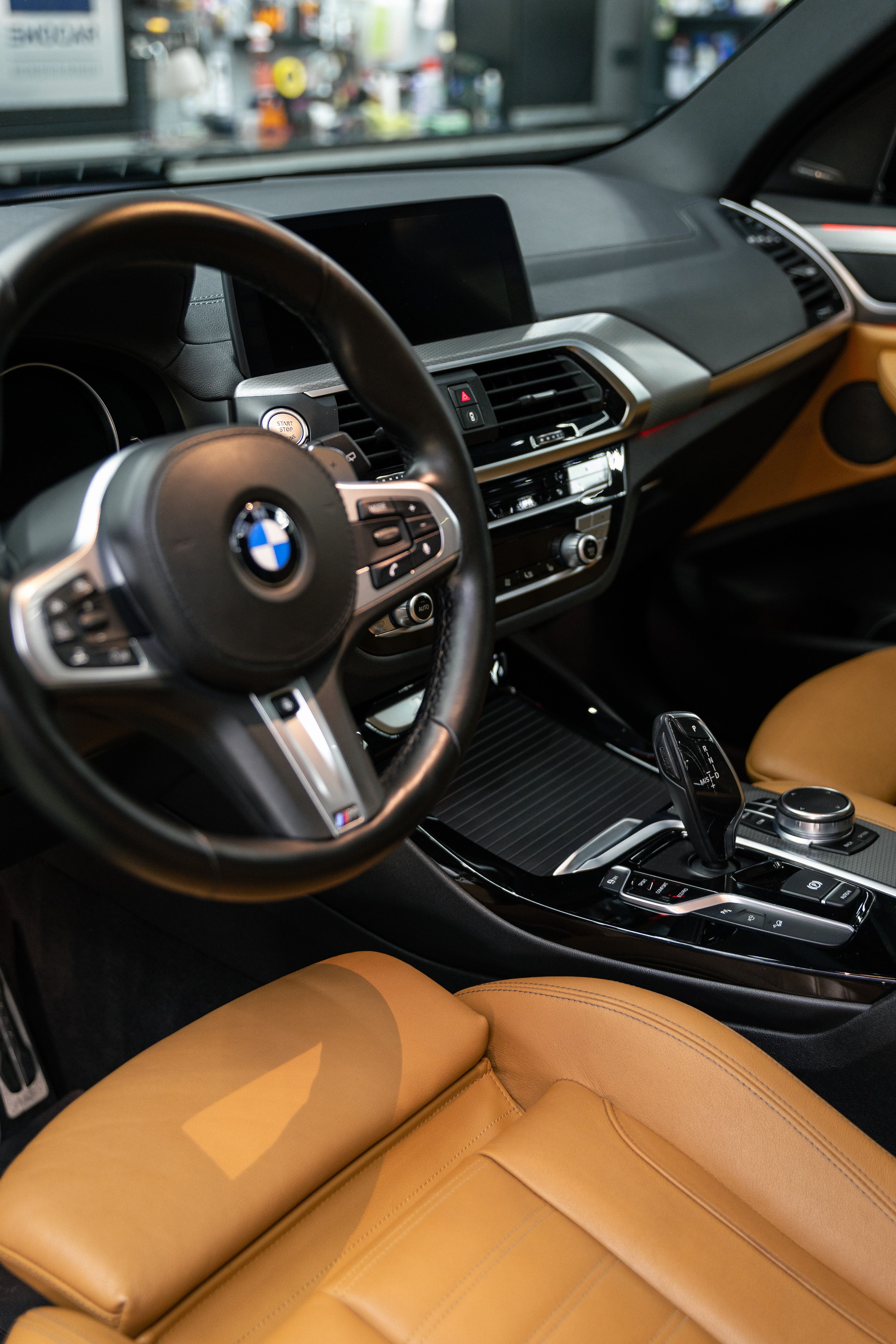 BMW car interior with tan leather seats, black dashboard, and steering wheel