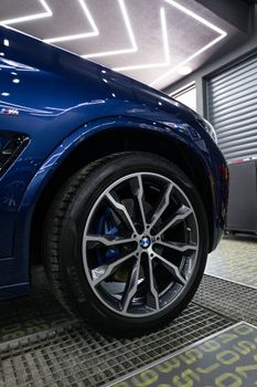 Close-up of a luxury blue BMW wheel showcased in a sleek, modern garage setting.