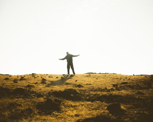 Free A man standing with open arms in a rural Indian field during a breathtaking sunset. Stock Photo