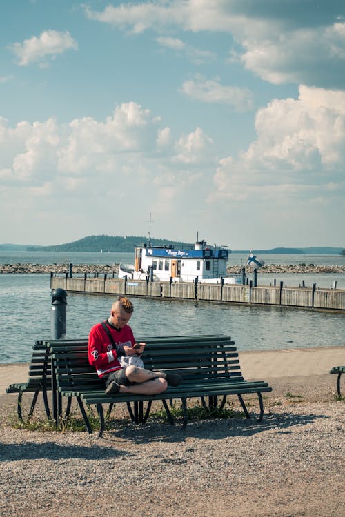 A man sitting on a bench next to a body of water