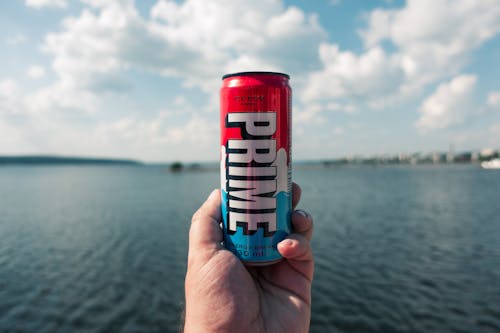 A person holding up a can of prime energy drink