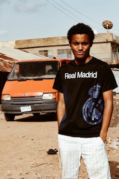 一名穿着休闲装的年轻人，在一辆橙色货车旁摆姿势