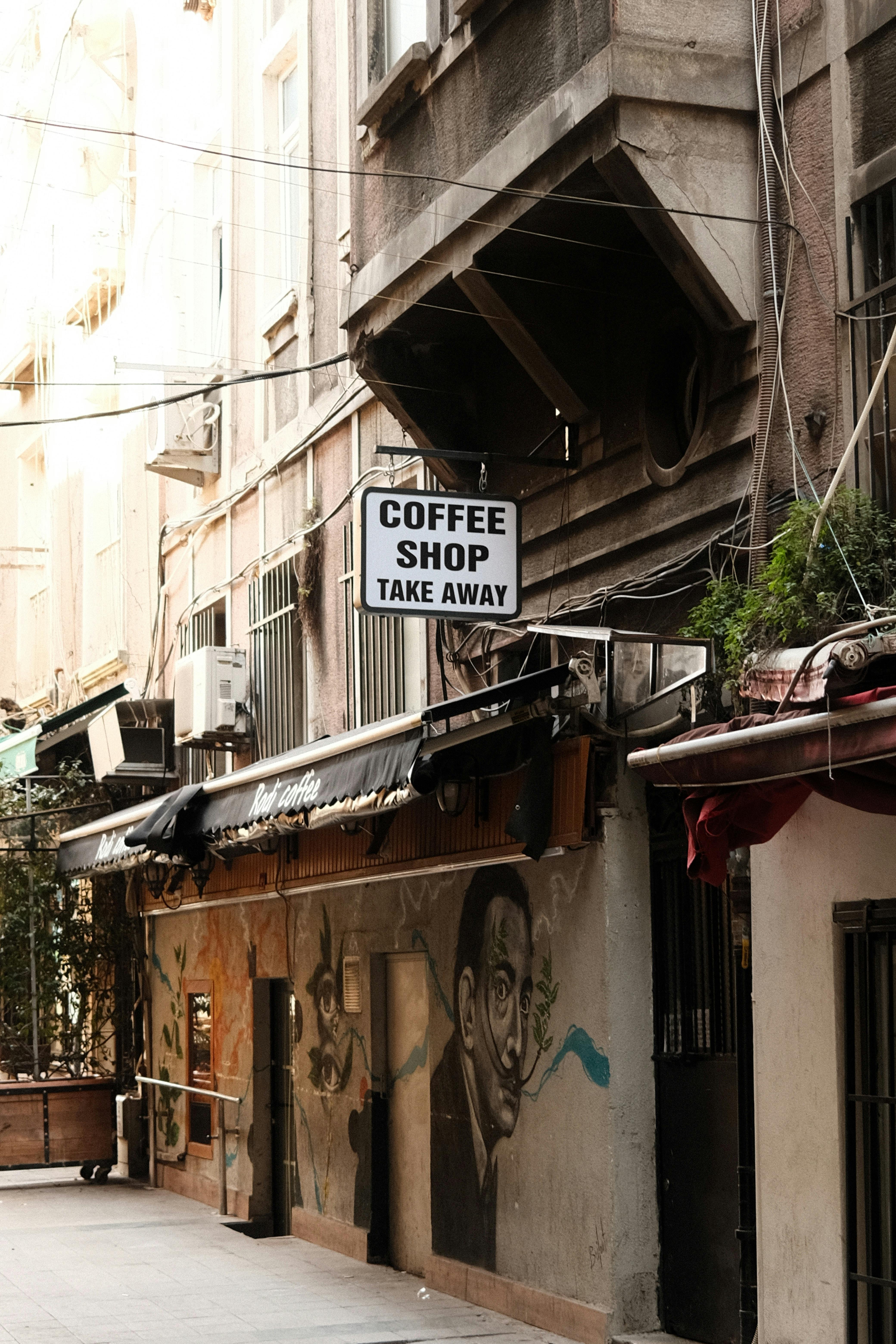 Urban street view of a coffee shop with mural in Istanbul, Türkiye, showcasing vibrant city life.