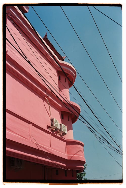 A pink building with wires and telephone poles