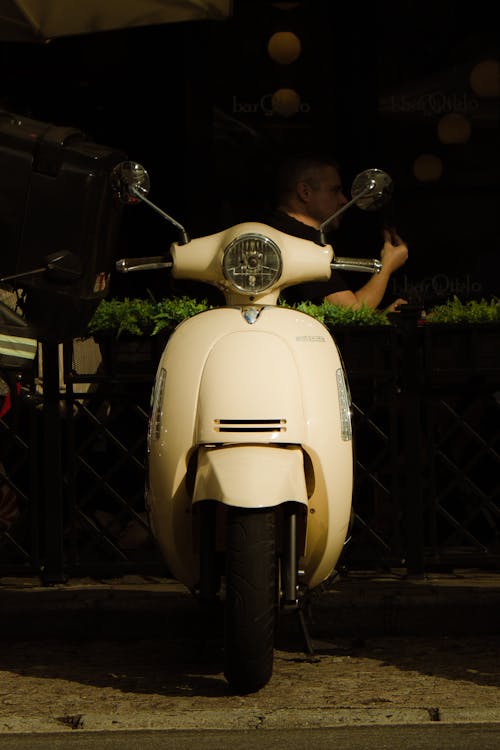 A white moped parked on a sidewalk next to a building