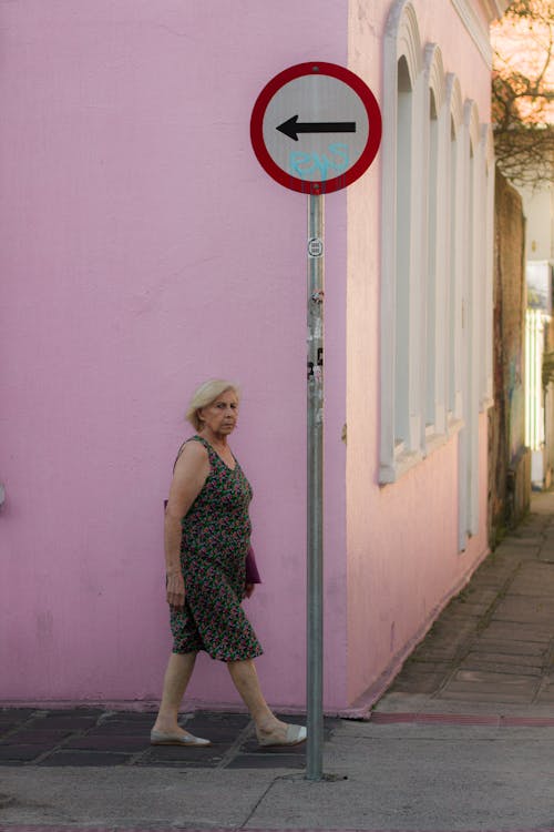 A woman walking down a street with a sign pointing to the right