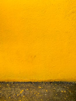 这面充满活力的黄色灰泥墙，纹理粗糙，以混凝土为基础，非常适合作为背景