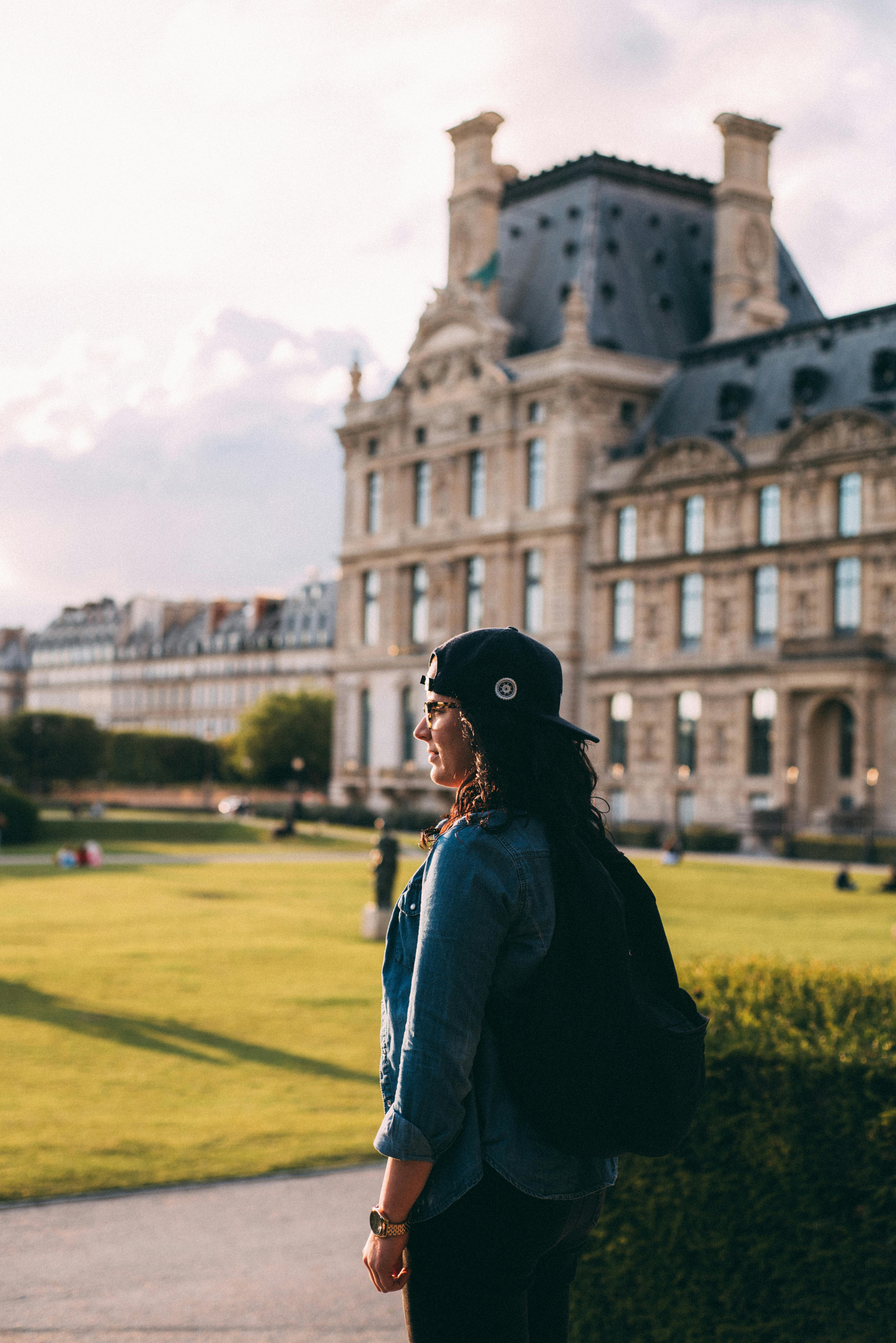 Glad girl in checkered shirt and blue jeans standing in park. Inspired  woman with leather backpack Stock Photo by look_studio