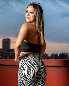 Elegant young woman in zebra leggings posing on a rooftop in Mexico City at sunset.