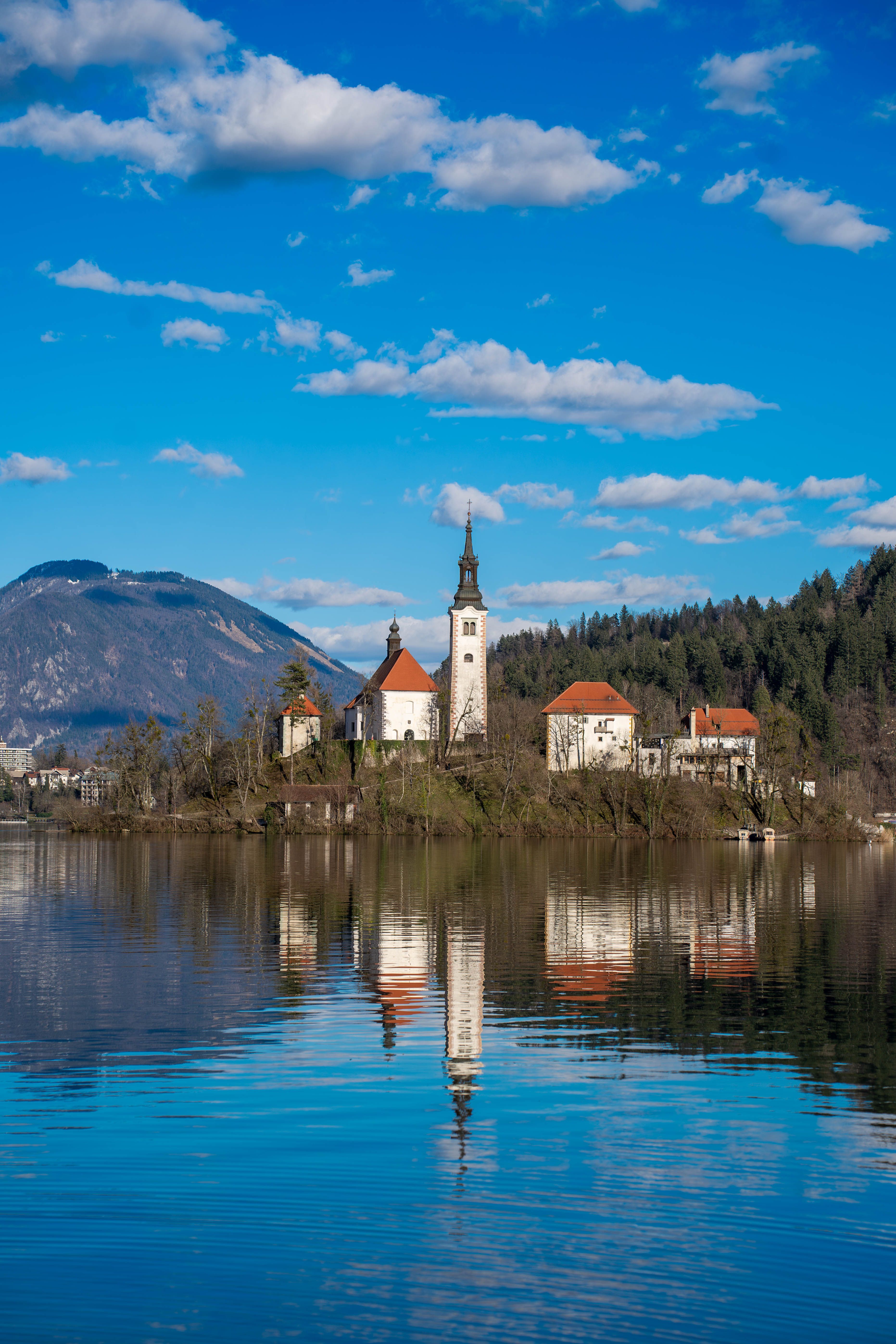 Vertical shot of Lake Bled with iconic church reflected in the still turquoise water