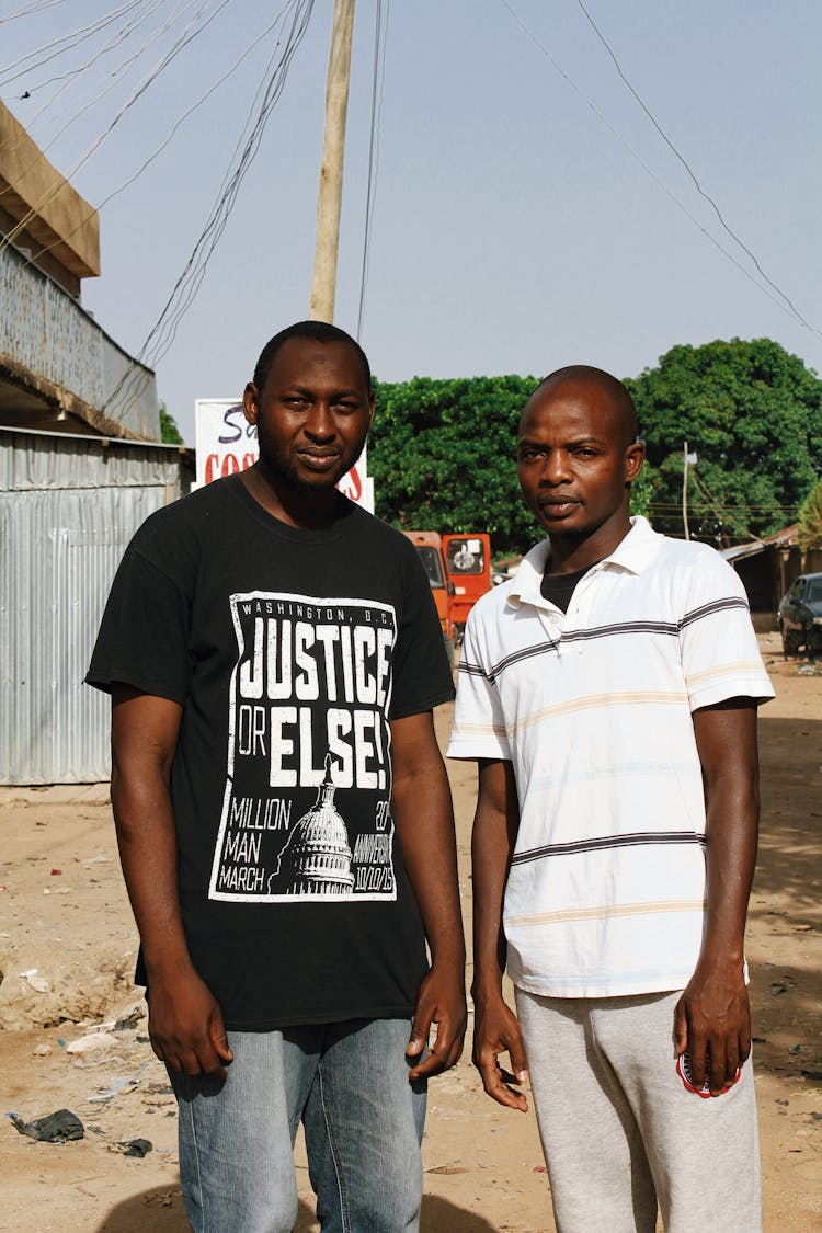 Photo Of Two Men Standing Near An Electric Pole