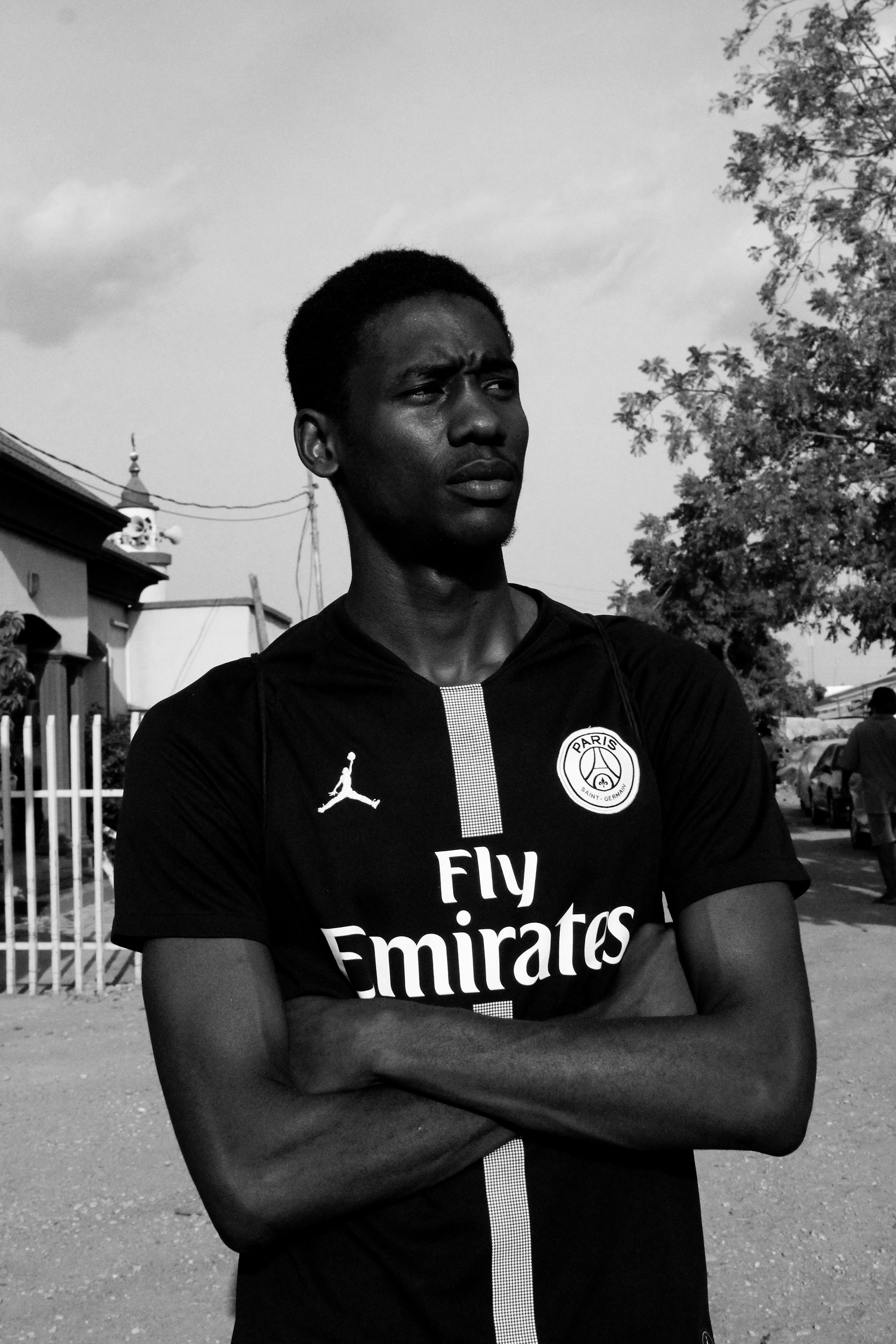 Grayscale Photo of Man in PSG Jersey With His Arms Crossed Looking Away · Free Stock Photo